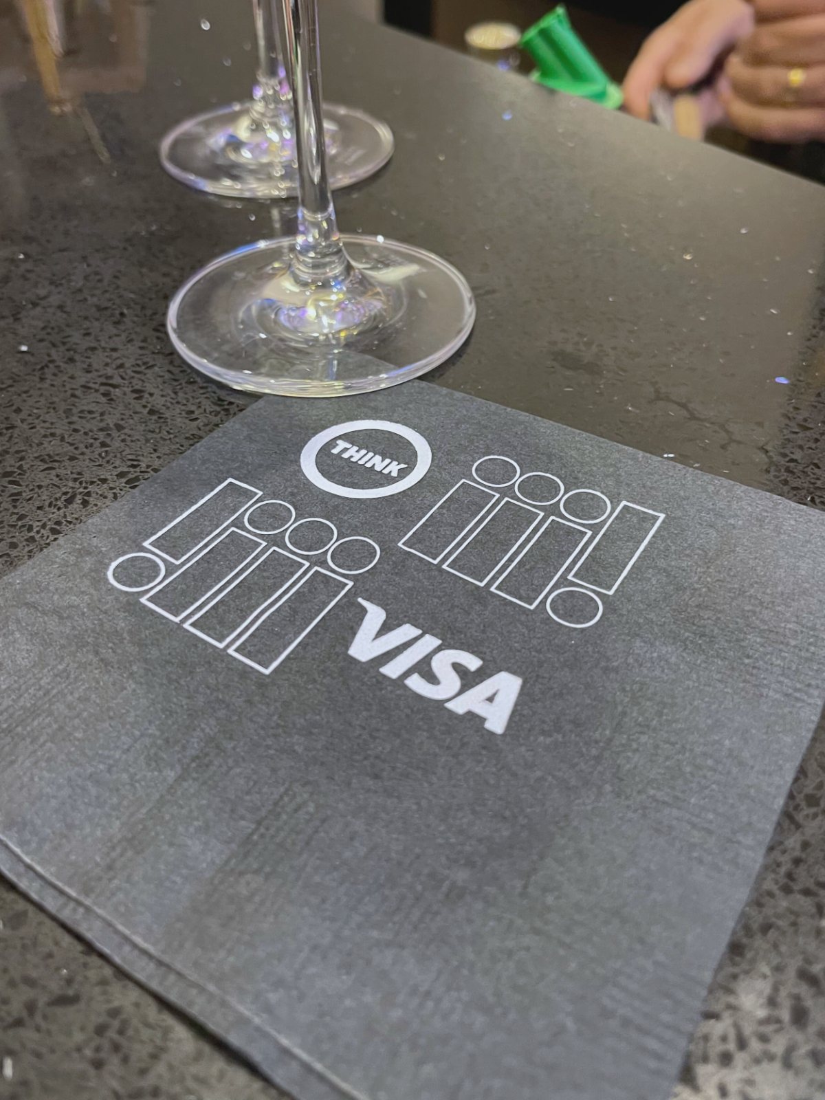 A THINK 24 cocktail napkin co-branded with Visa, carrying the exclamation pattern.